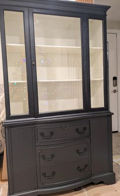 a black china cabinet with glass doors and drawers