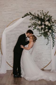 a bride and groom kissing in front of a wedding arch