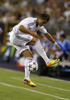 a man kicking a soccer ball on top of a field