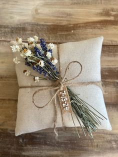 a small pillow tied with twine and flowers on top of a wooden floor next to a tag