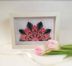 two tulips are sitting next to a white frame with black and pink designs on it