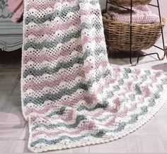 a crocheted blanket sitting on top of a wooden floor next to a basket