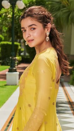 a young woman in a yellow dress posing for the camera with her hand on her hip