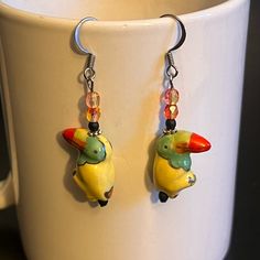 These Handcrafted One Of A Kind Earrings Are Made With Ceramic Toucans/Parrots, Czech Glass And Fish Hook Ear Wires. Earrings Measure 1 1/2”. Designed And Handcrafted By Me. Animal Parrot Toucan Amazon Rainforest Trees Nature Jewelry Artisan Art Jewelry Earrings Dangle Drop Dangly Glass Yellow Green Red Spring Summer Fall Handcrafted Handmade New To Poshmark? Make An Account And Use Code Ambentzen And Get $10 Off Your First Purchase Poshmark Ambassador 2 Posh Mentor Non Smoking Home Quick Shippi Playful Adjustable Yellow Earrings, Quirky Handmade Yellow Earrings, Amazon Rainforest Trees, Toucan Earrings, Rainforest Trees, Art Jewelry Earrings, Trees Nature, Amazon Rainforest, Nature Jewelry