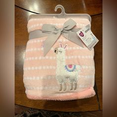 a pink blanket with an image of a llama on it and a gray bow