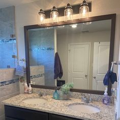 a bathroom vanity with two sinks and a large mirror over the sink that has three lights on it