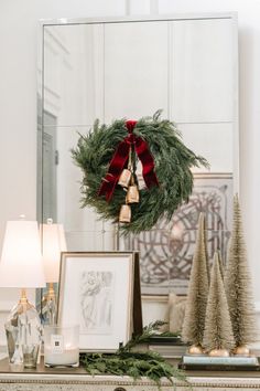 a christmas wreath on top of a dresser next to other holiday decorations and decor items