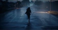 a woman is walking down the street at night