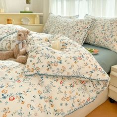 a teddy bear sitting on top of a bed next to pillows and pillowcases