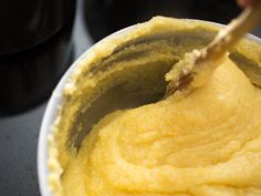 a bowl filled with yellow batter and a wooden spoon sticking out of the inside of it