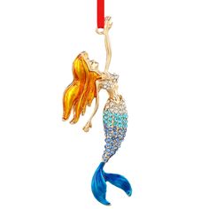 a gold and blue mermaid brooch with a red candle in the back, on a white background