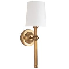 a brass wall light with a white shade