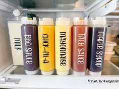 four bottles of juice sitting on top of an open refrigerator