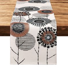 a table runner with black and white flowers on it, sitting on top of a wooden table