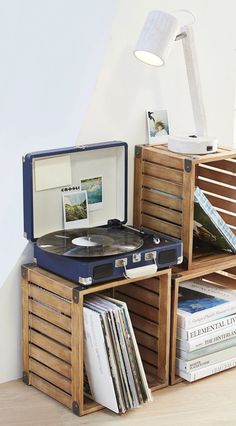 a record player sitting on top of a wooden table next to crates filled with records