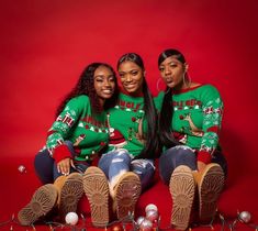 three women in ugly christmas sweaters sitting on the floor