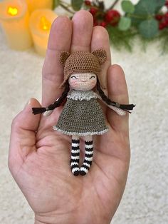 a hand holding a small crocheted doll in it's palm