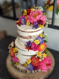 a multi - tiered wedding cake with colorful flowers on top