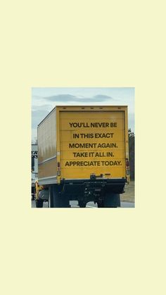 a yellow truck driving down the road with a message on it's rear end