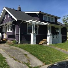 a purple house with white trim on the front porch and covered in grass, next to a sidewalk