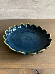 a blue and yellow bowl sitting on top of a wooden table next to a white wall