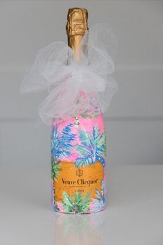 a bottle of wine with a bow on it's top and palm trees in the background