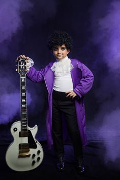 a man in purple coat holding an electric guitar