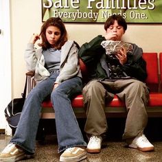 two people sitting on a bench in front of a sign that says safe families everybody man's one