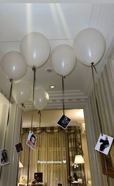 balloons are hanging from the ceiling in front of a mirror with pictures on it and photos attached to them