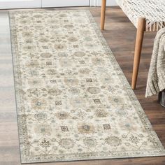 a white rug with an ornate design on the floor in front of a wooden table