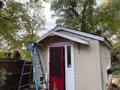 a small shed with a red door and ladder