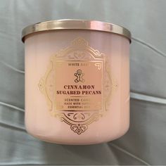 a candle that is sitting on top of a tablecloth covered wall with the words cinnamon sugared pecans printed on it