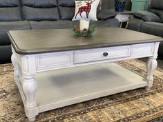 a white coffee table sitting on top of a rug in front of a gray couch