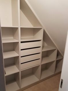 an attic bedroom with white shelving and shelves