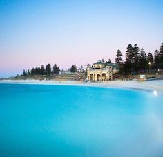 an ocean view with houses on the shore and blue water in front of it at dusk