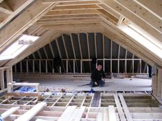 a man kneeling on the floor in an unfinished attic with wood framing around his feet