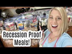 a woman standing in front of a counter filled with food and holding her finger up