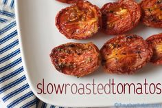 several tomatoes on a white plate with the word slow roasted tomatoes written in red lettering