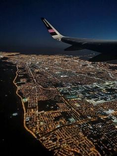 an airplane wing flying over a city at night