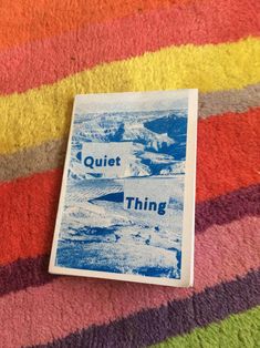 a book sitting on top of a colorful blanket next to a pile of books with the title quiet thing