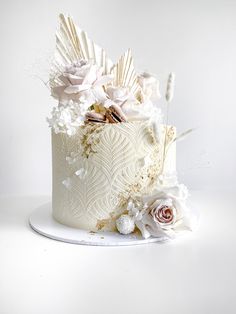 there is a white cake with flowers on the top and bottom layer, decorated with feathers