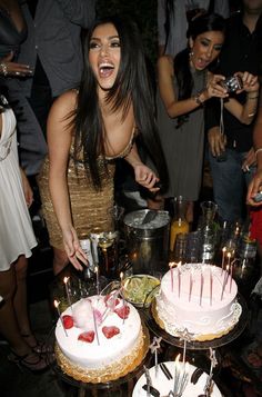 a woman cutting into a cake with candles on it