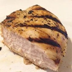 a piece of meat sitting on top of a white plate next to some black pepper