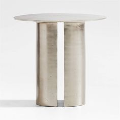 two round tables sitting side by side in front of a white wall and one is made out of metal