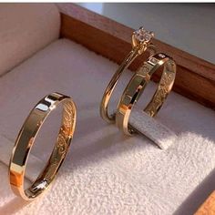 two gold wedding rings sitting on top of a white carpeted floor next to each other