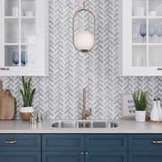 a kitchen with blue cabinets and white counter tops, gold pulls on the cupboards