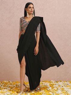 A two-piece Black and Peach Pre Draped Saree Set from the Label Nitika collection – Sunehra-Festive 2023. Featured here is a beautiful black pre draped saree set in lightweight drapery silk. It is paired with an embroidered blouse. The hand-embroidered folded floral sequins in symmetry along with peach-gold-silver gota stripes on the V neck blouse gives an elegant touch to this gorgeous, draped saree. This black pre draped saree set is an ideal outfit for special events. Pre Draped Saree, Indo Western Saree, Baby Pink Saree, Gota Embroidery, Black Embroidered Blouse, Mirror Work Saree, Draped Saree, Pleated Drapes, Ruffle Saree