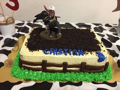 a cake that is on top of a table with dirt and grass in the shape of a cow