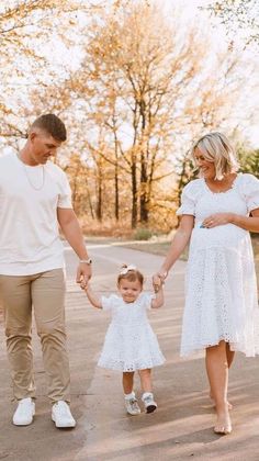 a man and woman holding hands while walking with a small child