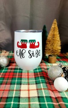 the elf did it coffee mug is sitting on a plaid tablecloth with ornaments around it